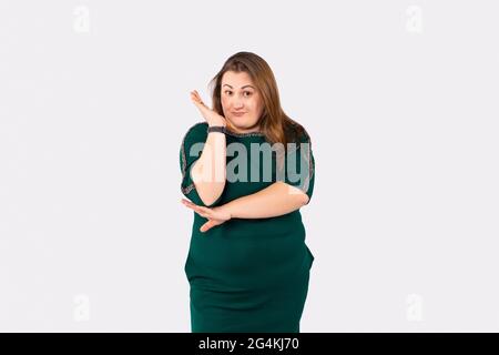 Una bella donna in piedi sui suoi piedi, con i capelli lunghi, ha messo la mano destra in su e guardando con un sorriso. Vestiti di grandi dimensioni. Foto Stock