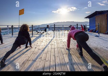 Donne che praticando yoga in una fattoria di cozze nella baia di Alfacs nel delta dell'Ebro (Tarragona, Catalogna, Spagna) ESP: Participantes en actividad de yoga (España) Foto Stock