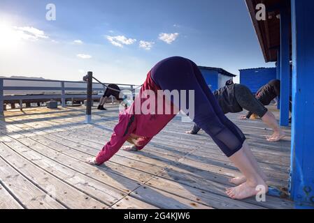 Donne che praticando yoga in una fattoria di cozze nella baia di Alfacs nel delta dell'Ebro (Tarragona, Catalogna, Spagna) ESP: Participantes en actividad de yoga (España) Foto Stock