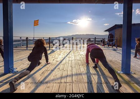 Donne che praticando yoga in una fattoria di cozze nella baia di Alfacs nel delta dell'Ebro (Tarragona, Catalogna, Spagna) ESP: Participantes en actividad de yoga (España) Foto Stock