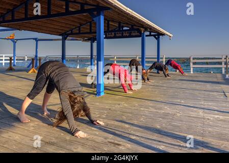 Donne che praticando yoga in una fattoria di cozze nella baia di Alfacs nel delta dell'Ebro (Tarragona, Catalogna, Spagna) ESP: Participantes en actividad de yoga (España) Foto Stock