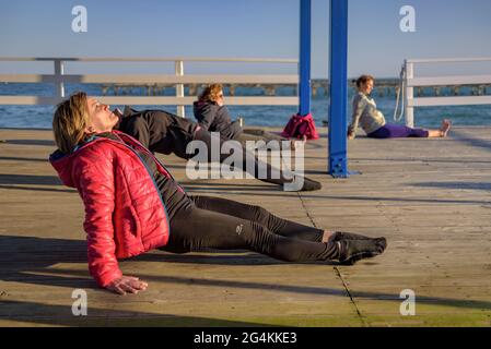 Donne che praticando yoga in una fattoria di cozze nella baia di Alfacs nel delta dell'Ebro (Tarragona, Catalogna, Spagna) ESP: Participantes en actividad de yoga (España) Foto Stock