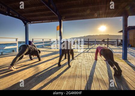 Donne che praticando yoga in una fattoria di cozze nella baia di Alfacs nel delta dell'Ebro (Tarragona, Catalogna, Spagna) ESP: Participantes en actividad de yoga (España) Foto Stock