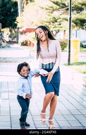 Happy Mother Son Couple Godetevi il parco giochi della città divertendosi e ridendo insieme - mamma nera e bambini ride e sorriso ritratto Foto Stock