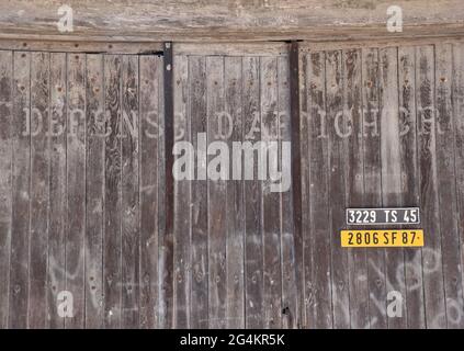 Una grande serie di vecchi cancelli in legno da garage, recanti l'immagine chiara ma spettrale delle parole DFFENSE DE'AFFICHER, francese per No Bill Posting Foto Stock