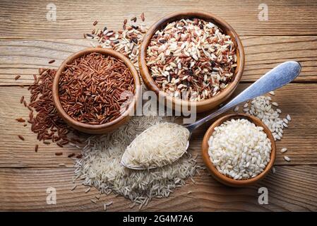 Quattro tipi di riso: basmati, mescola grano lungo, arborio e riso rosso su fondo ligneo. Vista dall'alto Foto Stock