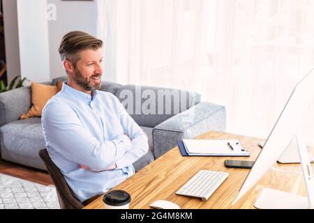 Ripresa di un uomo d'affari seduto dietro il suo computer e che ha discussione e riunione online in videochiamata. Riunione di affari in linea. Lavoro di squadra. Foto Stock