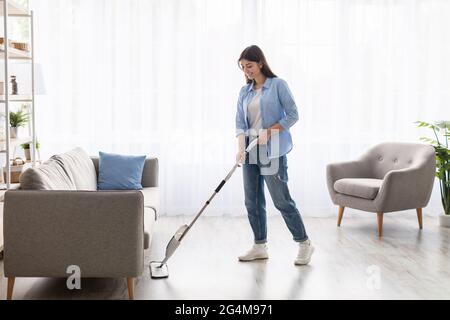 Ritratto di donna sorridente che pulisce il pavimento con mop spray Foto Stock