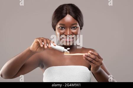 Igiene orale. Bella donna nera che applica il dentifricio sullo spazzolino di bambù Eco Foto Stock