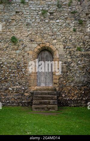 Vecchia porta di legno in pietra nel muro di un forte medievale. Foto Stock