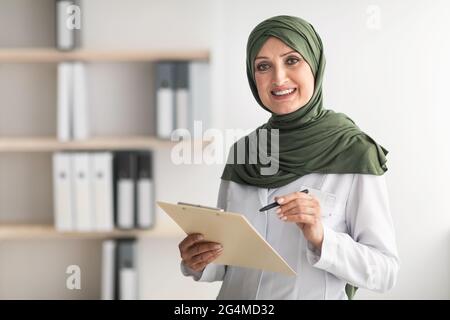 Felice musulmana femmina Dottore in posa in piedi in moderna clinica Office Foto Stock