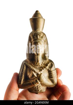 Foto isolata della mano umana che tiene in mano statuetta dell'antichità del faraone d'oro. Foto Stock