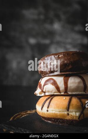 Pila di tre diverse ciambelle fresche con glassa di cioccolato e caramello su una tavola di legno Foto Stock