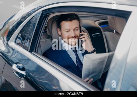 Uomo d'affari elegante in stile formale che viaggia in auto di lusso Foto Stock