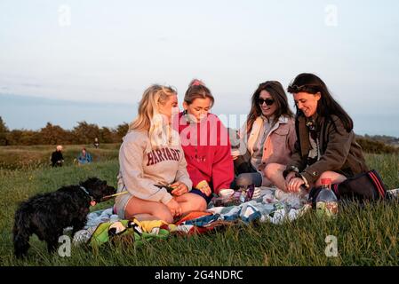 Contea di Meath, Irlanda. 21 Giugno 2021. Quattro giovani donne che hanno pic-nic e guardare il tramonto.centinaia di persone si sono riuniti nella collina di Tara ieri sera per il Solstice Estate del 2021. Ogni anno, la gente si riunisce sulla collina di Tara per celebrare il solstizio estivo, che è stato un luogo spirituale e storico per migliaia di anni. (Foto di Natalia Campos/SOPA Images/Sipa USA) Credit: Sipa USA/Alamy Live News Foto Stock