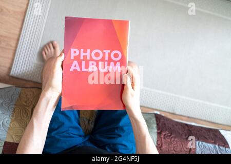 vista dall'alto delle mani di una persona che tiene il libro di album fotografico rosso, nostalgia di famiglia Foto Stock