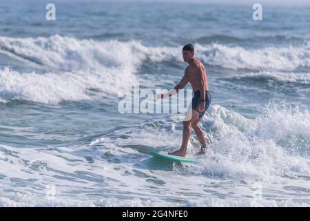 Un uomo surfs vicino alla spiaggia al Johnson Beach National Seashore in Florida il 26 marzo 2021. Foto Stock