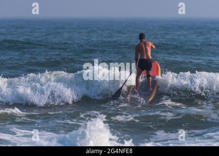 Un uomo surfs vicino alla spiaggia al Johnson Beach National Seashore in Florida il 26 marzo 2021. Foto Stock