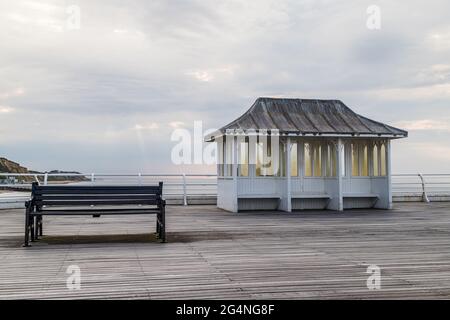 Panchina e rifugio sul Molo Cromer sulla costa nord del Norfolk visto prima del tramonto. Foto Stock