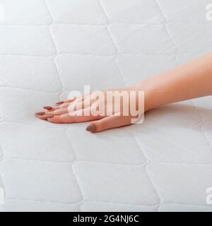 Donna che sceglie il nuovo materasso. Pressione manuale femminile materasso di prova per controllare la morbidezza. Scelta di comodi materassi per dormire in negozio. Controllo di qualità Foto Stock