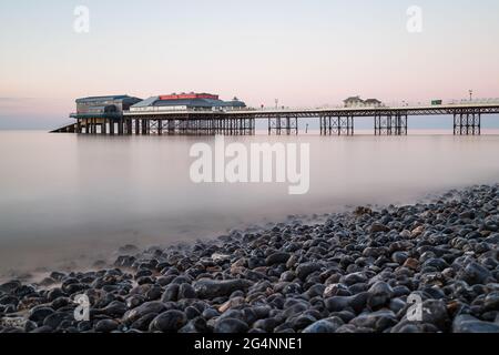 Molo Cromer visto sopra la spiaggia di ciottoli in una lunga esposizione presa nel giugno 2021 sulla costa nord del Norfolk. Foto Stock