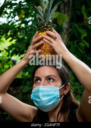 Ritratto di una donna latina in piedi teso con un ananas sulla sua testa Foto Stock