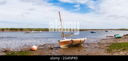 Un panorama multi immagine preso a Burnham Overy Staithe sulla costa nord del Norfolk di barche da pesca ormeggiate in un canale nel giugno 2021, come la marea viene io Foto Stock