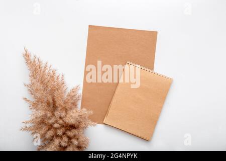 Terroso beige colore bianco carta artigianale nota invito mockup con fiore secco ramo pampas Reed. I notepad Mockup marroni sono vuoti per il biglietto d'auguri Foto Stock