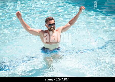 felice uomo bearded in occhiali da sole divertirsi in piscina acqua nelle vacanze estive, vacanze estive. Foto Stock