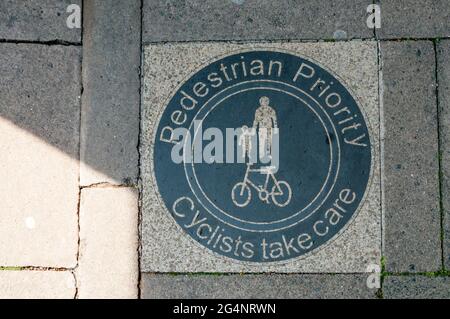 Un cartello con la scritta pedoni priorità ciclisti si prendono cura, sullo spazio di circolazione condiviso in Hammersmith. Foto Stock