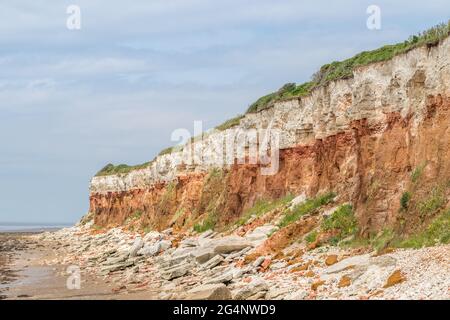 Le scogliere di Hunstanton a bassa marea si vedono nell'estate del 2021 con le rocce dai colori striati che cadono nel mare. Foto Stock