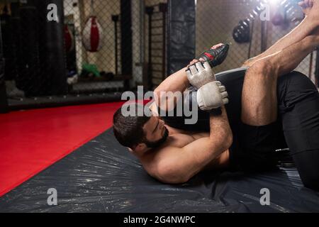 Grappler cercando di soffocare l'avversario in lotta a terra, allenamento in palestra. Due uomini atletici impegnati in mma, pugilato, lotta senza regole Foto Stock