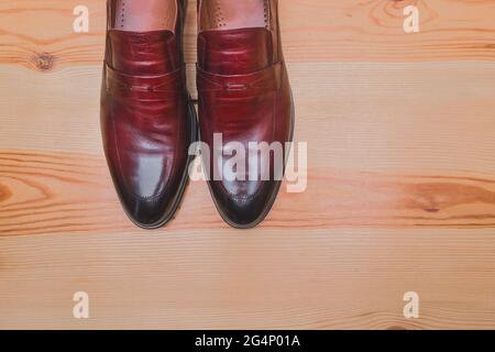 Scarpe da uomo realizzate in pelle naturale marrone rossa stand su un pavimento in legno spazio copia sfondo. Foto Stock