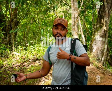 Minca, Magdalena, Colombia - 19 2021 maggio: L'uomo latino bruno con la sua pelle indossa un cappuccio e si trova nella foresta circondata da un lotto di natura Foto Stock