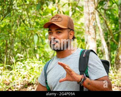 Minca, Magdalena, Colombia - 19 2021 maggio: L'uomo latino bruno con la sua pelle indossa un cappuccio e si trova nella foresta circondata da un lotto di natura Foto Stock
