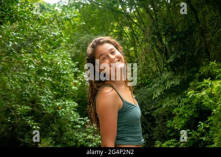 Minca, Magdalena, Colombia - 19 2021 maggio: Donna caucasica sorride alla macchina fotografica e splende dai raggi del sole vicino al fiume Foto Stock