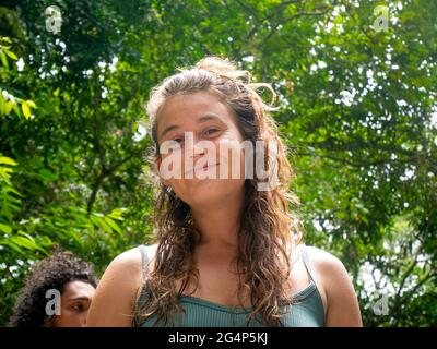 Minca, Magdalena, Colombia - 19 2021 maggio: Donna caucasica sorride alla macchina fotografica e splende dai raggi del sole vicino al fiume Foto Stock