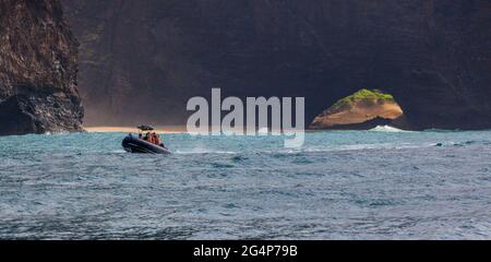 Uno zodiaco di turisti gode delle suggestive formazioni laviche che cadono nell'oceano Pacifico lungo LA COSTA NA PALI - KAUI, HAWAII Foto Stock