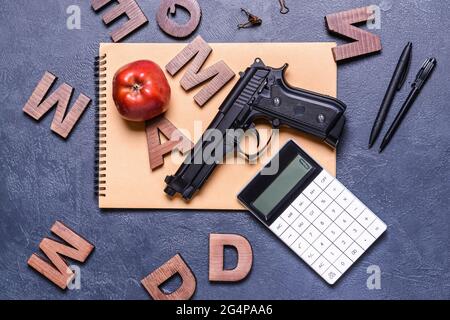 Pistola e cancelleria su sfondo scuro. Concetto di ripresa scolastica Foto Stock