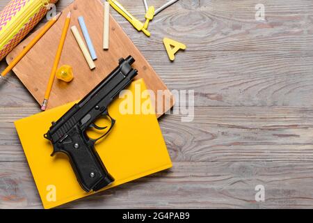 Pistola e cancelleria su sfondo di legno. Concetto di ripresa scolastica Foto Stock