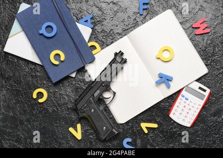 Pistola e cancelleria su sfondo scuro. Concetto di ripresa scolastica Foto Stock