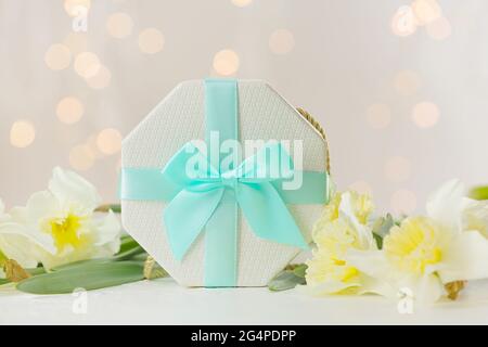 Confezione regalo e bellissimi fiori sul tavolo contro le luci offuscate Foto Stock