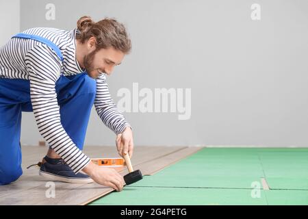 Falegname che installa pavimenti in laminato in camera Foto Stock