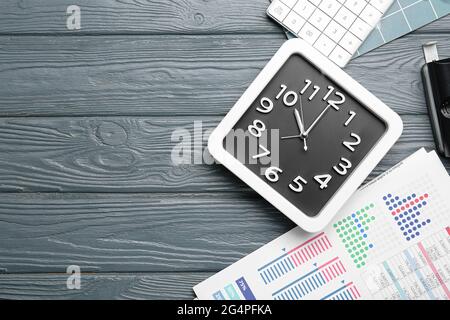 Composizione con orologio elegante e grafico di affari su sfondo di legno scuro Foto Stock