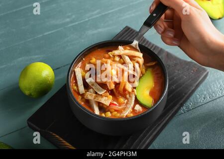 Donna che mangia gustosa zuppa di pollo enchilada dalla ciotola sul tavolo Foto Stock