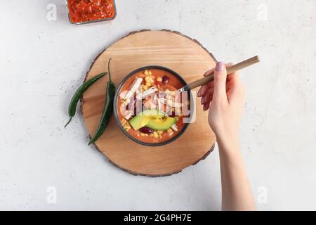 Donna che mangia gustosa zuppa di pollo enchilada dalla ciotola sul tavolo Foto Stock