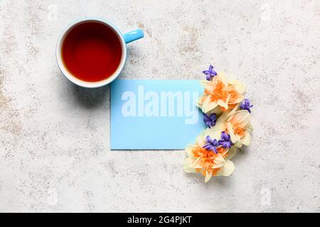 Tazza di tè, bellissimi fiori e carta bianca su sfondo chiaro Foto Stock