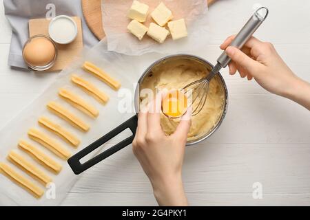 Donna che fa churros gustosi su sfondo di legno chiaro Foto Stock