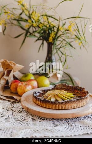 Torta di mele rustica, servita con gelato e frutti di bosco con fiori da tavola. Servito su un piatto di legno pigro Susan. Foto Stock