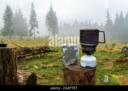 Cucina nella foresta. Cibo liofilizzato in una confezione. Cibo essiccato e stufa a gas. Prima colazione nella foresta. Cibo in un pacchetto. Foto Stock